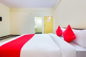 a bedroom with a white bed with red pillows at Hotel O Sai Residency Near SR Nagar metro station in Hyderabad +32 photos