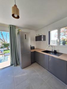 a kitchen with a stainless steel refrigerator next to a window at Échappée Belle à Marzan in Marzan