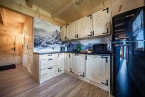 een keuken met witte kasten en een zwarte koelkast bij Topory Prestige House sauna & jacuzzi in Zakopane