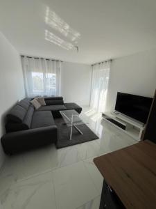 a living room with a black couch and a television at Maison proximité de la plage in Plouzané
