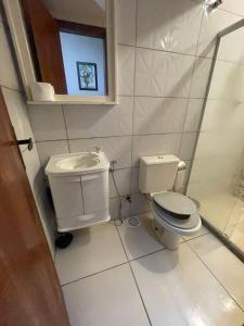a white bathroom with a toilet and a sink at Casa Centro Terreo in Campos dos Goytacazes +4 photos