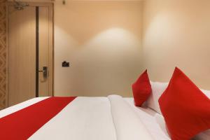 a bedroom with a white bed with red pillows at Collection O Hotel Harriot in Somarda Kauasot