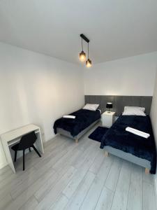 a bedroom with two beds and a table and a desk at MC Apartamenty Ściegiennego 3 in Augustów