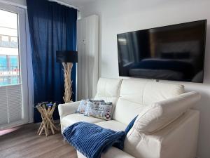 a white couch in a living room with a large tv at Maritimes Luxusapartment in Rostock