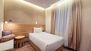 a small room with a bed and a chair at Hotel Bankir Khiva in Khiva