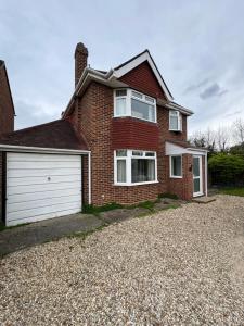 ein rotes Backsteinhaus mit einer weißen Garage in der Unterkunft Oxford 3 Bedroom Detached House, with Large Garden and Private Parking in Kidlington