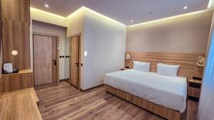 a bedroom with a large white bed and wooden floors at Hotel Bankir Khiva in Khiva