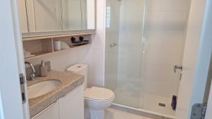 a white bathroom with a toilet and a shower at Ilha Pura Barra in Rio de Janeiro