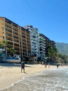 a man standing on the beach in front of a hotel at Penthouse Vallarta in Puerto Vallarta