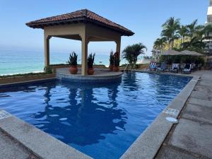 a swimming pool with a gazebo next to the ocean at Penthouse Vallarta in Puerto Vallarta