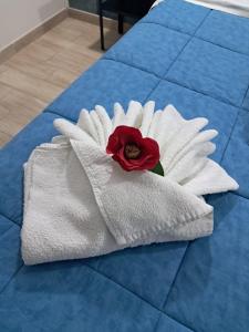 a white towel with a red rose on a bed at La Petite Maison in Naples