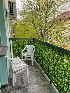 two chairs sitting on a balcony next to a hedge at Stan na dan Alexa sa free parkingom in Novi Sad