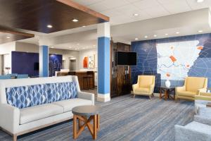 a lobby with a couch and chairs and a tv at Holiday Inn Express & Suites West Memphis by IHG in West Memphis