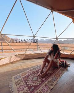 a girl sitting on a rug in a tent looking out at the desert at Queen's Magic Camp in Wadi Rum