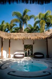 Higuera BlancaにあるDepartamento en Litibu Punta Mitaのヤシの木と茅葺き屋根のプール付きのリゾート
