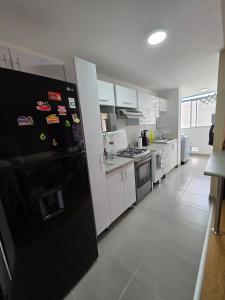 a kitchen with a black refrigerator and white cabinets at Minidepartamento en Ñaña in Chosica