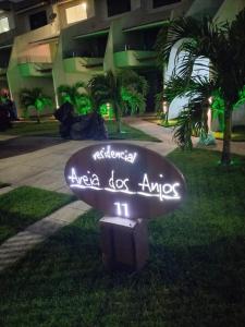 a sign in the grass in front of a building at Suíte com Pé na Areia, Praia dos anjos in Arraial do Cabo