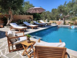 a swimming pool with chairs and an umbrella next to it at Suite Home Villa Paxos in Gaios