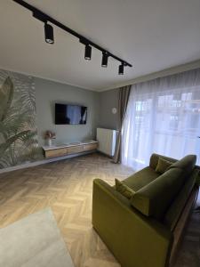 a living room with a green couch and a flat screen tv at Reda City EnergyApart in Szczecin +3 photos