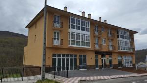 a large yellow building with windows on a street at Pension-Albergue Lemos in Treacastela