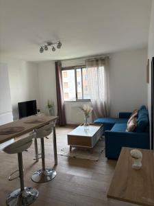 Una sala de estar con un sofá azul y una mesa. en Charmant T2 rénové, en Lyon