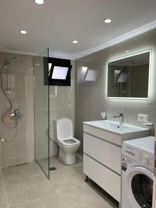 a bathroom with a toilet and a sink and a washing machine at Vila Mehmeti in Delvinë +24 photos