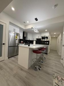 a kitchen with white cabinets and a counter with stools at Maxti Guest Suite, Northwest Calgary in YYC +63 photos