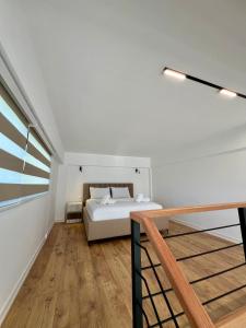 a white bedroom with a bed and a staircase at Vila Mehmeti in Delvinë
