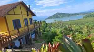 a yellow house with a view of the water at Suíte Coqueiros Paraty in Paraty