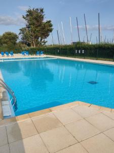 una grande piscina blu con sedie blu di Résidence Bretagne Douce excellent emplacement 300m de la mer ad Arzon