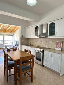 a kitchen with white cabinets and a wooden table with chairs at Spacious Lovely Apartment in Sarandë