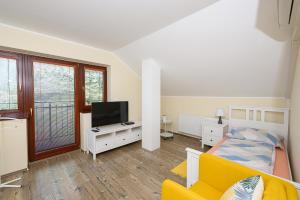 a living room with a yellow couch and a television at Penzión Walter in Veľké Úľany