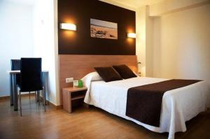 a bedroom with a bed and a desk and a chair at Hostal Rocamar in Santander