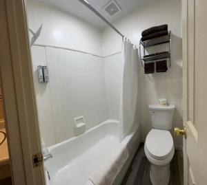a white bathroom with a toilet and a bath tub at Harper Motel in Harper