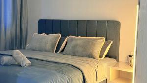a bed with a blue headboard and two pillows at Iconic Regency Service Residences - Xin's Home in Bayan Lepas