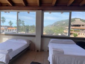 two beds in a room with a view of a mountain at La Altanera in Troncones