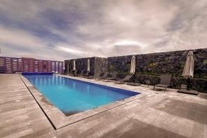 a swimming pool with chairs and umbrellas next to a building at Miravento Zibatá - Refugio Cálido y Familiar in La Cañada