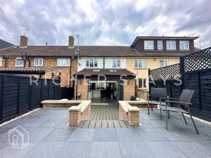 a house with a patio with benches and a fence at Premium 3BR House, French Doors and Private Garden in Borehamwood