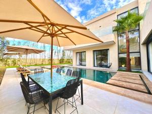 a patio with a table with chairs and an umbrella at Modern Villa Assia in Marrakesh