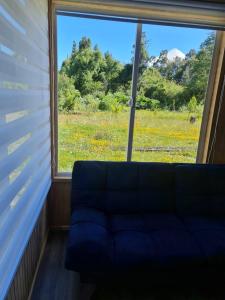 a blue couch in a room with a large window at Cabañas Costabudy in La Ensenada +3 photos