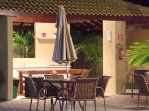 a table and chairs with an umbrella on a patio at Soft Guarajuba -Lindo Village Residencial amplo 2 quartos com suite e varanda no Térreo in Guarajuba