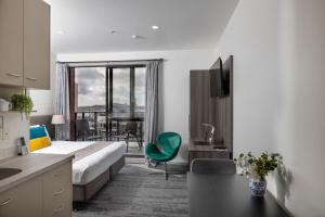 a hotel room with a bed and a desk and a kitchen at Quest on Eden Auckland CBD Apartment Hotel in Auckland