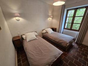 two beds in a small room with a window at Maison ancienne en campagne avec jardin clos - Animaux acceptés - Proche vignobles Chinon - FR-1-381-440 in Parçay-sur-Vienne