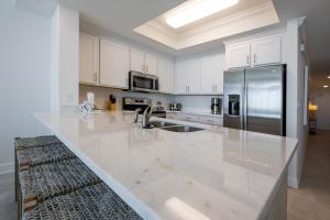 a kitchen with white cabinets and a stainless steel refrigerator at Phoenix Gulf Towers 906 condo in Gulf Shores