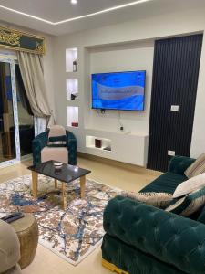 a living room with a couch and a tv on a wall at Wealthy in Madīnat ash Shurūq