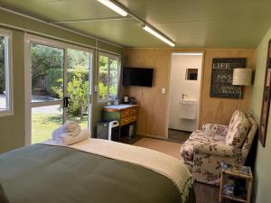 a bedroom with a bed and a chair and a window at Jen's Oasis in Paraparaumu