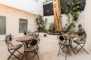 a patio with tables and chairs and a tree at Habitación triple confort - Casa Esmeralda in San José
