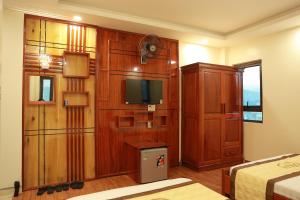 a bedroom with a tv in a wooden wall at Gold Hotel in Bản Gùm
