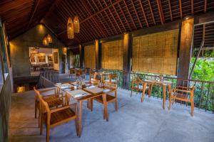 a restaurant with wooden tables and chairs on a patio at Purana Suite Ubud in Ubud