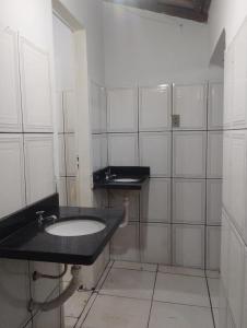 a bathroom with a black sink and white tiled walls at Chacara para Aluguel Recanto Eco vida Cuiaba in Cuiabá